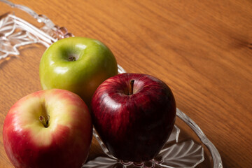 mixture of apples, red and green apples, in transparent glass container on wooden table.