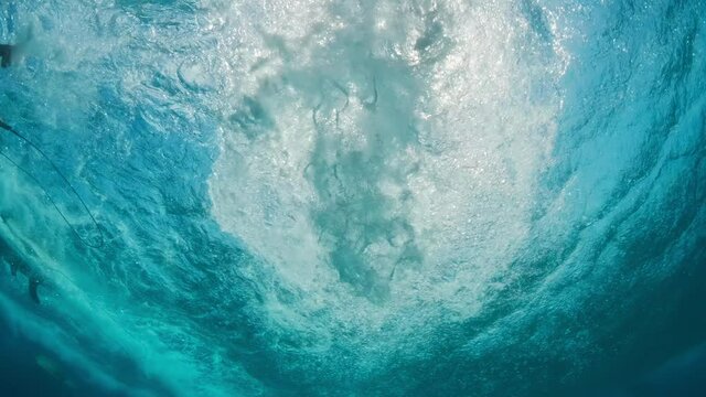 Underwater view of the bodyboarder paddling and taking off