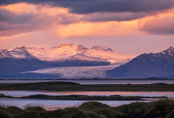 Obraz premium Sunrise Stokksnes cape sea beach, Iceland. Amazing nature scenery, popular travel destination. Autumn grass on black volcanic sand dunes.