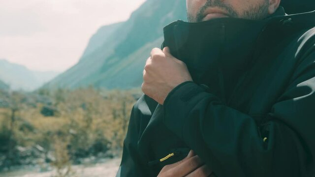 A man sits on the edge of a cliff wearing a black anorak. Katu-Yaryk canyon Chulyshman Valley. Altai