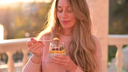 Woman eating a fruit salad with chia seeds in a park at the sunset - Powered by Adobe