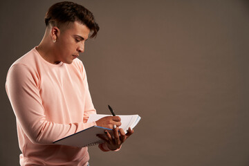 latin man writing in notebook standing facing down