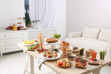 Dishes with different food on table in living room. Luxury brunch