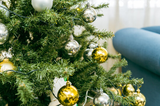 Closeup Detail Of A Christmas Tree With Gold And Silver Baubles In The Living Room Of A House