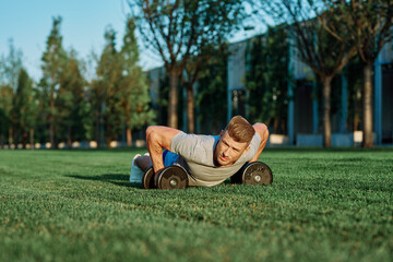 Fototapeta premium athletic man training with dumbbells in the morning Park