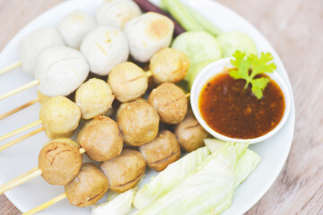 Asian Thai food grilled meatballs fishball and porkball with spicy sauce, Meatballs on skewers on white plate and fresh vegetables cabbage yard long bean cucumber