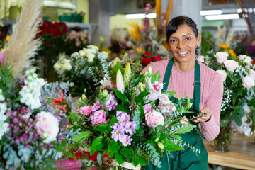 Fototapeta premium Florist in an apron creates bouquets in a flower shop