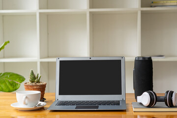 Laptop computer and coffee mug with headphones, books, speakers on a businessman's desk.