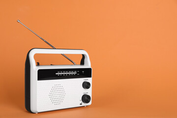 Portable retro radio receiver on orange background. Space for text