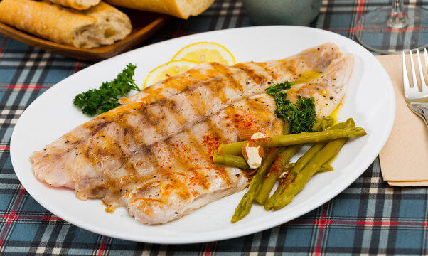Appetizing baked ocean perch fillet with baked asparagus, sliced lemon and greens ..