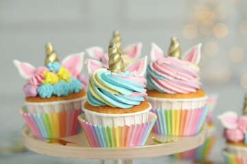 Dessert stand with cute sweet unicorn cupcakes  against blurred lights, closeup