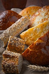 Assorted whole grain breads and baguettes with a wheat stalk.
