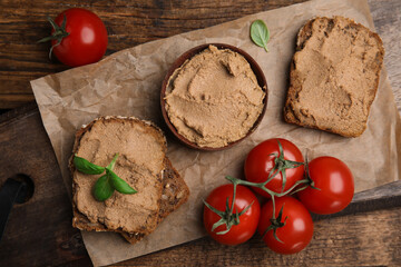Fresh bread with delicious meat pate, cherry tomatoes and basil on wooden table, flat lay