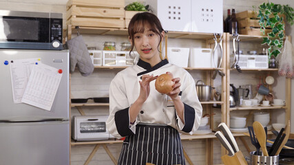 attractive cook talking to camera is giving tips for buying fresh onions . taiwanese young lady in chef’s whites is blogging about food preparation in the kitchen.