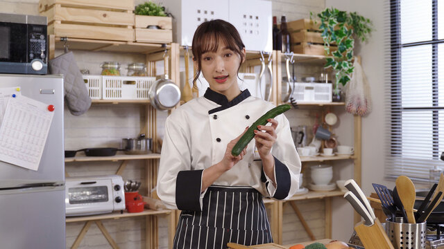 young culinary specialist holding cucumber, starting her online video teaching audience how to choose fresh vegetables. live streaming cooking tutorial at home concept.