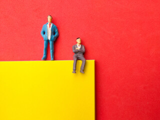 Miniature people on red background.Copy space.