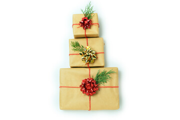Three gifts boxes in the form of Christmas tree of craft paper tied with a red rope and a bow.