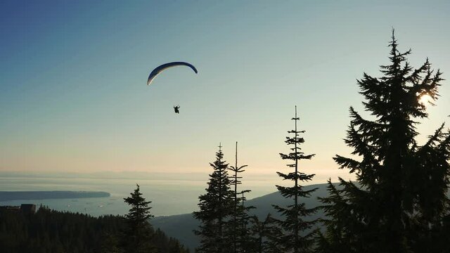 paraglider flying over grouse mountain with the city of Vancouver in the background, British Columbia, Canada in 4K