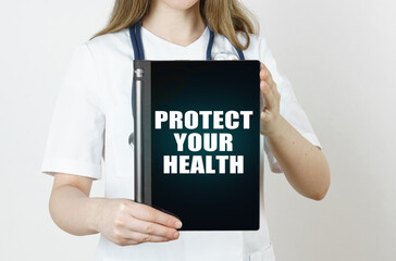 Fototapeta na wymiar The doctor is holding a tablet with the inscription - PROTECT YOUR HEALTH