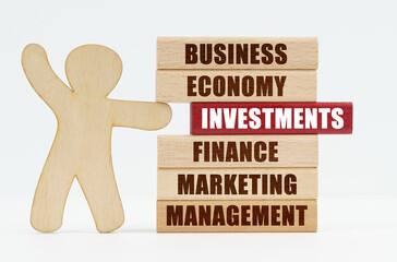On a white background, a wooden man pushes out of the wall a red wooden sign with the inscription - investments