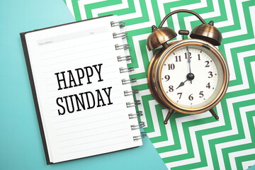 Happy Sunday text and alarm clock on blue background