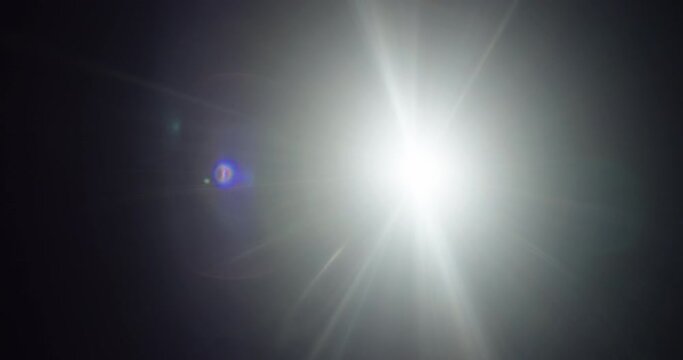 Lens flare made with hand modified vintage lens and custom filters. The light source moves left to right as purple reflections and beams of light move with it.