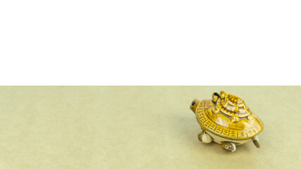 yellow turtle figurine of the symbol of wisdom on a light background with white