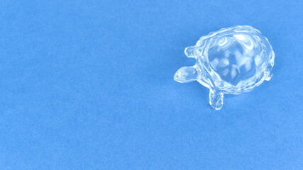 plastic transparent figurine of a turtle on a blue background, photo from above