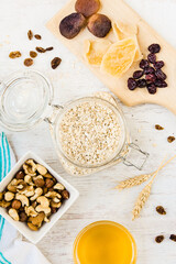 Top view of raw ingredients for homemade granola preparation - oats, nuts, honey and dried fruits. Healthy eating.