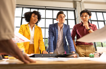 Young designer giving some new ideas about project to his partners in conference room. Business people discussing over new business project in office.Confident and successful team.