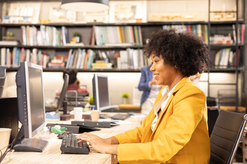 Fototapeta premium Young African American female architect working in an office.Portrait of a confident black businesswoman with all african american team in working room.
