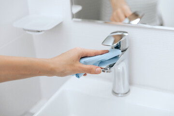 Cleaning the sink faucet with a microfiber cloth. Cleaning the bathroom. Sanitize surfaces...