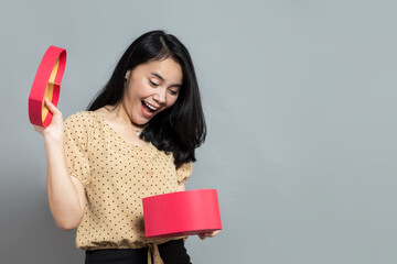 Beautiful woman with surprised expression when opening heart shaped gift box