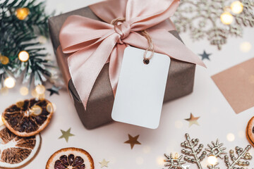 Gift box wrapped in craft paper and empty tag. Mockup. Festive Christmas concept.