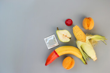 Fruits and vegetables, condoms on a gray background. The concept of sex education. Flat lay. Top...