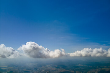 Aerial view from airplane window at high altitude of earth covered with white puffy cumulus clouds