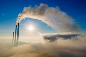 Aerial view of coal power plant high pipes with black smoke moving up polluting atmosphere at sunset