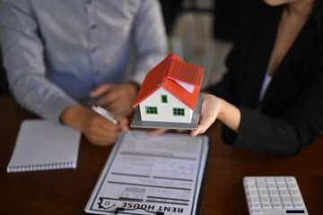 Real estate agent holding small house model. Insurance or loan real estate concept.