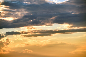 Bright landscape of dark clouds on yellow sunset sky in evening.