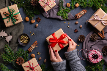 Christmas concept, female hands wrapping handmade eco friendly gift boxes