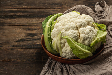 Beautiful cauliflower with green leaves in a ceramic bowl