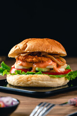 Fresh tasty chicken burger on wood table. Sandwich with chicken burger, tomatoes, pickled cucumber and fried egg. Fresh tasty chicken burger on wooden table.