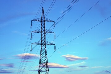 Torres de alta tensión para conducción de electricidad. Fotografía tomada al atardecer con unas bonitas nubes de colores cálidos en el cielo.