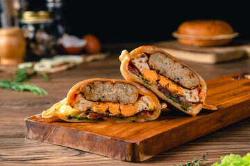 Fresh tasty Ufo Chicken Burger on wood table. Sandwich with chicken burger, tomatoes, pickled...