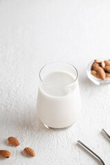 Vegan almond milk in glass with nuts on white background. Copy space. Healthy vegetarian food. selective focus. Non dairy alternative milk