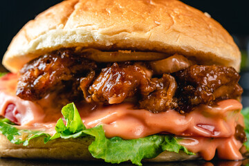 Fresh tasty chicken teriyaki burger on wood table. Sandwich with chicken burger, tomatoes, pickled...