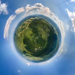 Little planet globe with dark mountain hills covered with green mixed pine and lush woods...