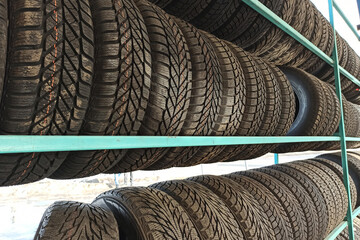 Many black rubber car tires on store shelf for sale