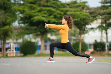 young woman runner stretching legs before run in park