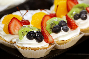 Creamy cake with fresh fruits and berries. Sweet dessert with blueberries, strawberries, kiwi, and tangerines